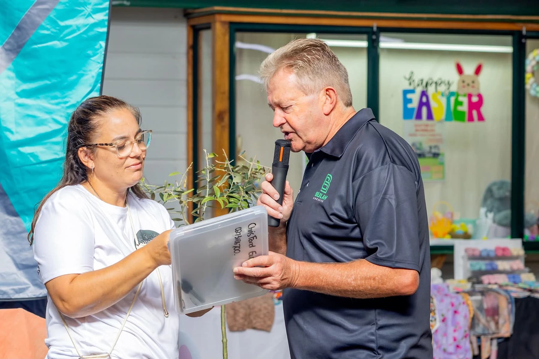 Chris Ford beside a speaker with a microphone at Easter at Riverslea